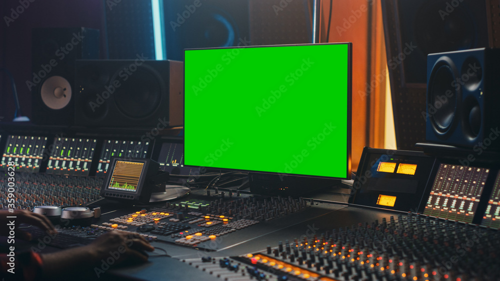 Poster portrait of stylish audio engineer working in music record studio, uses green screen computer, mixer