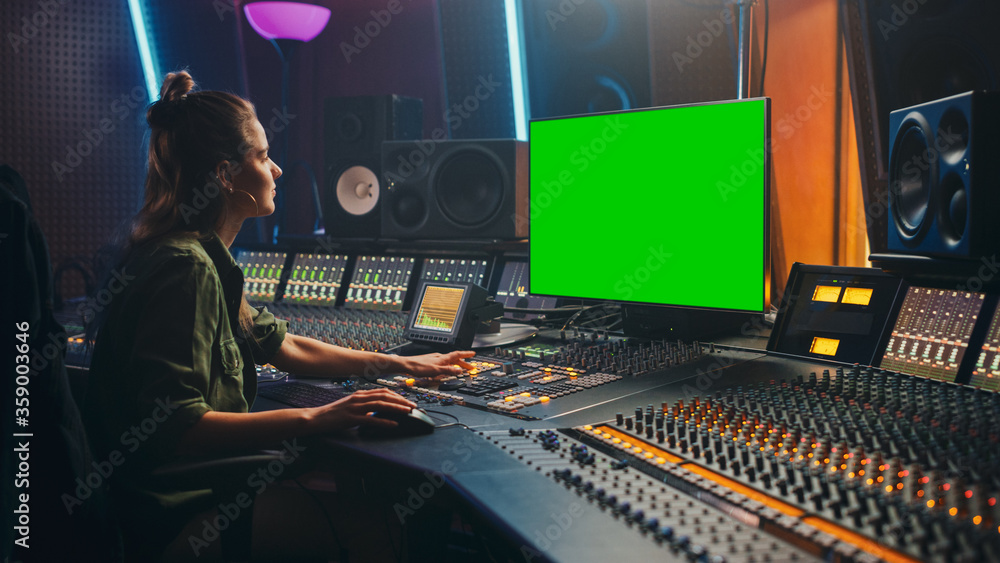 Poster portrait of stylish female audio engineer / producer working in music record studio, uses green scre
