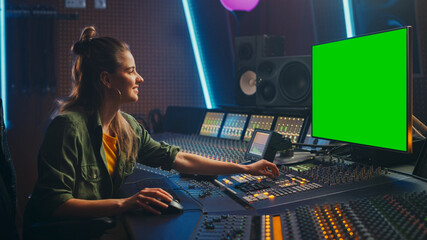 Portrait of Stylish Female Audio Engineer / Producer Working in Music Record Studio, Uses Green Screen Computer Display, Mixer Board, Control Desk to Create New Song. Creative Artist Musician 