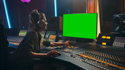 Stylish Female Audio Engineer / Producer Working in Music Record Studio, Uses Headphones, Green...