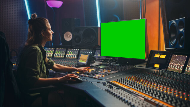 Portrait of Stylish Female Audio Engineer / Producer Working in Music Record Studio, Uses Green Screen Computer, Mixer Board, Control Desk to Create New Song.