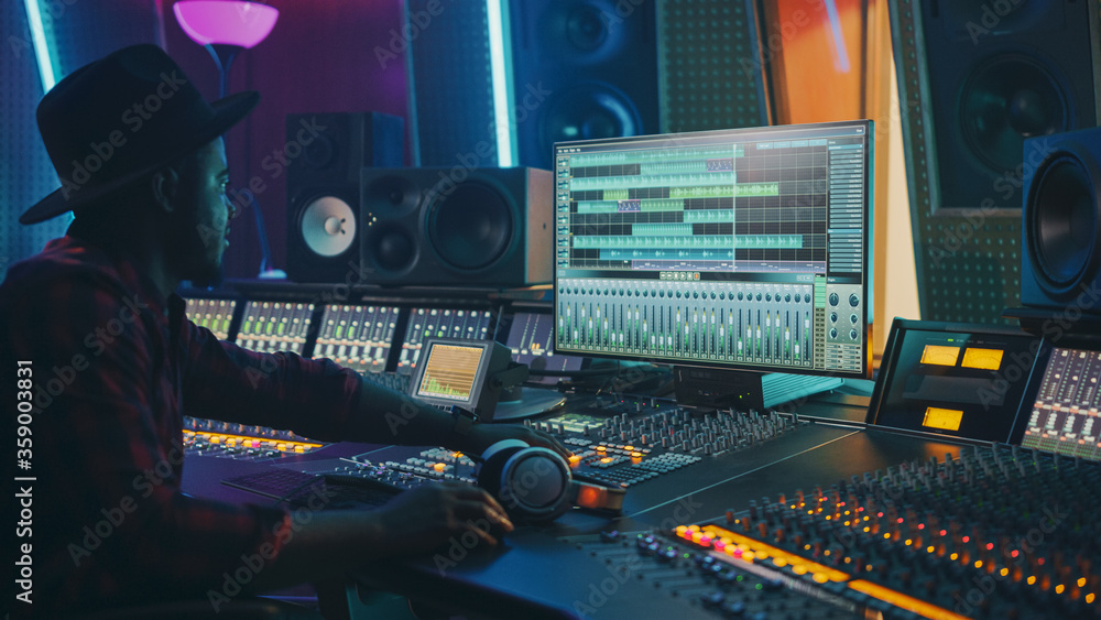 Poster stylish audio engineer working in music recording studio, uses mixing board and software to create m