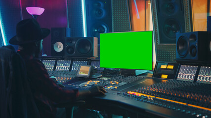 Stylish Audio Engineer / Producer Working in Music Record Studio, Uses Green Screen Chroma key Computer Display, Mixer Board Equalizer and Control Desk to Create New Hit Song. Black Artist Musician