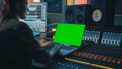 Female Artist, Musician, Producer, Audio Engineer Working in Music Record Studio on a New Album, Use Green Screen Laptop Computer, Control Desk for Mixing and Creating Hit Song. Over Shoulder