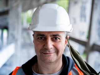 The man removes the protective mask from his face to symbolize the end of the pandemic. Portrait of a male Builder in a construction helmet and a medical antiviral mask.