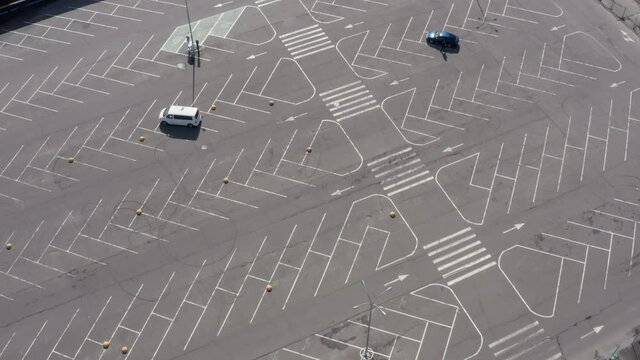 Several cars in the middle of a large empty parking lot outside the supermarket during quarantine with plenty unused parking space. Helix Aerial Drone Shot.