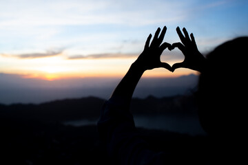 girl shows heart with her hands. on the volcano batur. bali. Indonesia