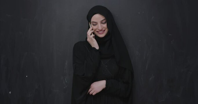 Muslim woman using smart phone over black chalkboard