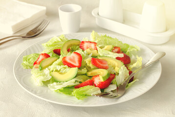 Salad with avocado, strawberries and lettuce on white background