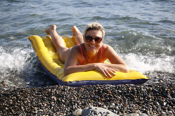 Happy woman smiling in sunglasses on an air mattress by the sea
