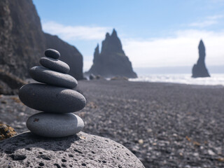 Zen Stone stacks or cairn on black sand beach near Reynisfjara rocks. Balanced pebbles pyramid. Concept of harmony and meditation, Iceland
