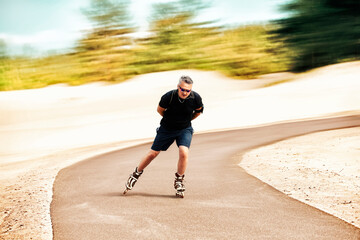 Middle-aged man rides inline skates on an asphalt track