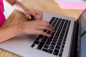 Fototapeta na wymiar hands of a girl on the keyboard of a laptop