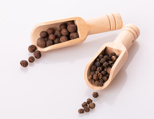black pepper peas in a wooden spoon and scattered isolated on a white background
