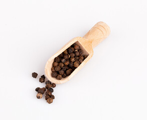 black pepper peas in a wooden spoon and scattered isolated on a white background