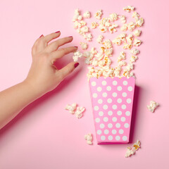 Obraz na płótnie Canvas Paper box with popcorn on pink background