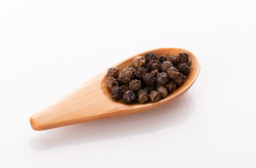 black pepper peas in a wooden spoon and scattered isolated on a white background