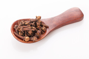 clove seasoning in a wooden spoon isolated on a white background