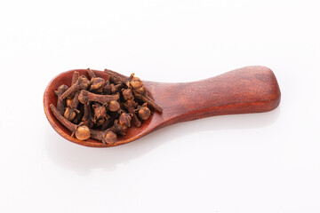 clove seasoning in a wooden spoon isolated on a white background