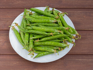 ripe juicy green peas in a plate on a wooden table