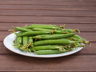 ripe juicy green peas in a plate on a wooden table