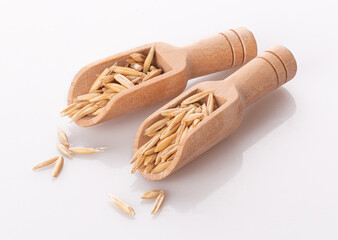 oat grains in a wooden spoon isolated on a white background