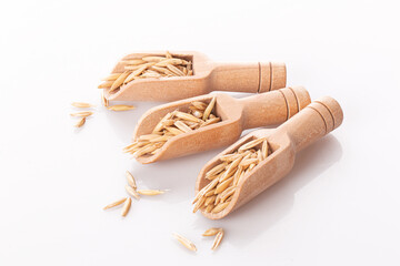 oat grains in a wooden spoon isolated on a white background