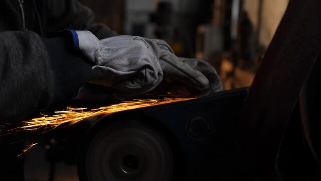 Herrero lijando metal en su forja. 