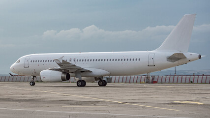 Side view of airplane. White commercial passenger jet airliner on airport apron. Cloudy sky background. Modern technology in fast transportation, business travel aviation, tourism charter flights.