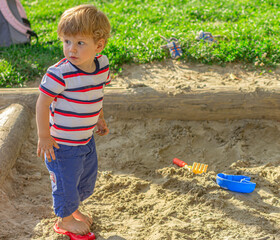 child plays with sand in a sandbox