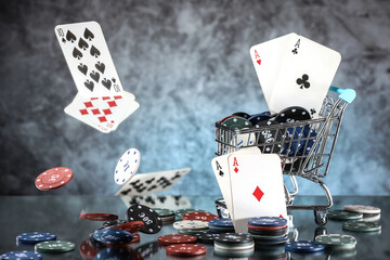 A pair of aces, hearts and diamonds, on a deck of playing cards. Poker playing chips on a dark and light blue background. Online gambling. Addiction. Falling playing cards and poker chips