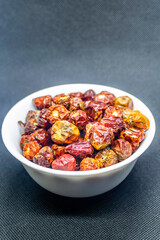 a bunch of round red chillies in a white bowl