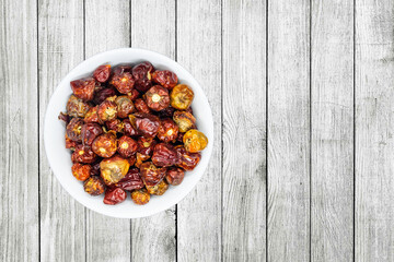 A bunch of round red chillies in white bowl in a nice wooden background