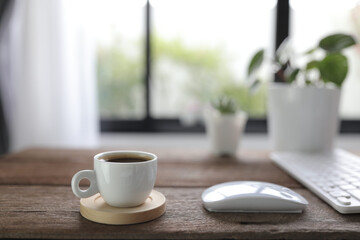 White coffee cup with mouse and keyboard on rustic wooden dinning table interior home
