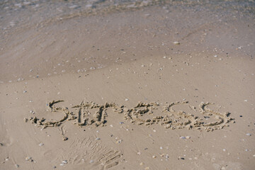 word stress written in the sand and near it a sea wave
