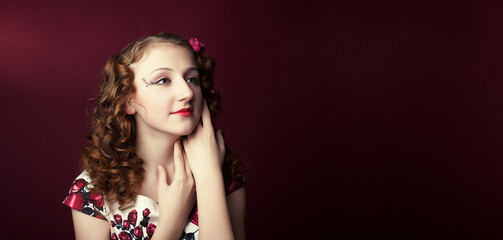 Fototapeta premium Portrait of a cute girl in pin-up style on red paper background. Stylish photography in vintage style.
