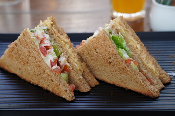 Two club sandwiches placed on a black plate at a restaurant. Close-up photo of a club sandwich....