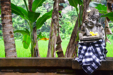 The bali guardian stone sculpture with sarong cloth at the Bali street.