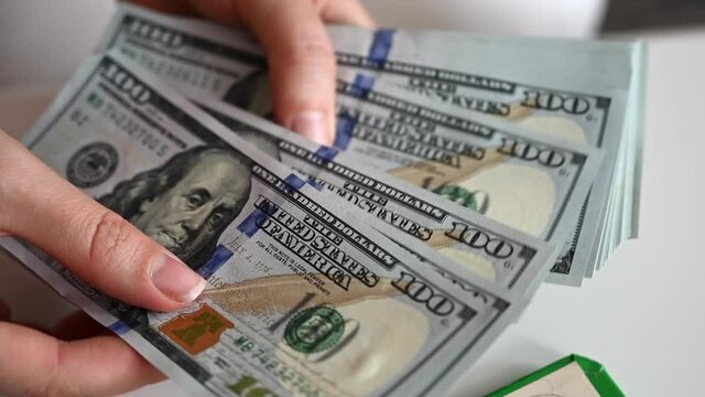 Man hand counting us dollars with nominal of 100, slow motion close up