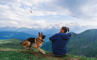 A man traveler and a dog sit in the mountains, Georgia, Svaneti