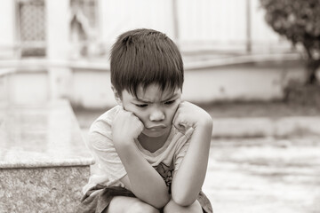 Sepia tone. 5​-6​ years​ old​ child.​ Alone​ Asian​ little​ boy​ feel​ sad, angry​ and​ stressed.​ He​ lonely at​ the​ playground.​ Unhappy kid.​ Mood and​ emotions.
