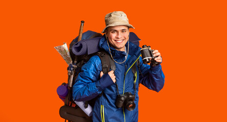 Hiker with binoculars smiling over orange background