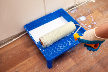 The painter dips the roller in a bath with a primer