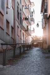 Fototapeta premium Vertical shot with a shallow depth of field of a typical sloping narrow street of Portugal with a metal banister, paving-stone on the ground facades of residential houses with closed windows on sides