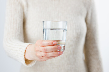 A woman holds a glass of water in her hands.