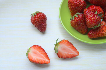 Red cut organic strawberries on table, ripe strawberry fruits in the plate