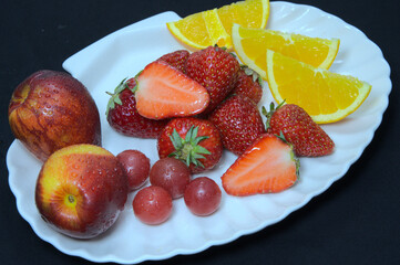 Various fruits on white plate, fruit platter, strawberries, nectarines, oranges and grapes