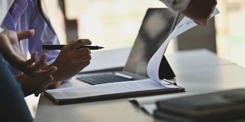 Businesspeople are working together with paperwork on the clipboard at the working desk.