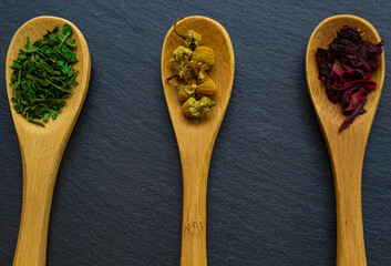 Spices background on wooden spoons. Parsley, chamomile, hibiscus