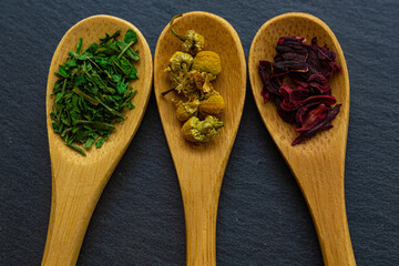 Spices background on wooden spoons. Parsley, chamomile, hibiscus
